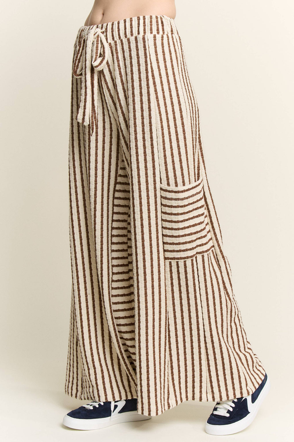 Brown and cream striped wide-leg pants featuring a drawstring waist, relaxed fit, and oversized front patch pockets.