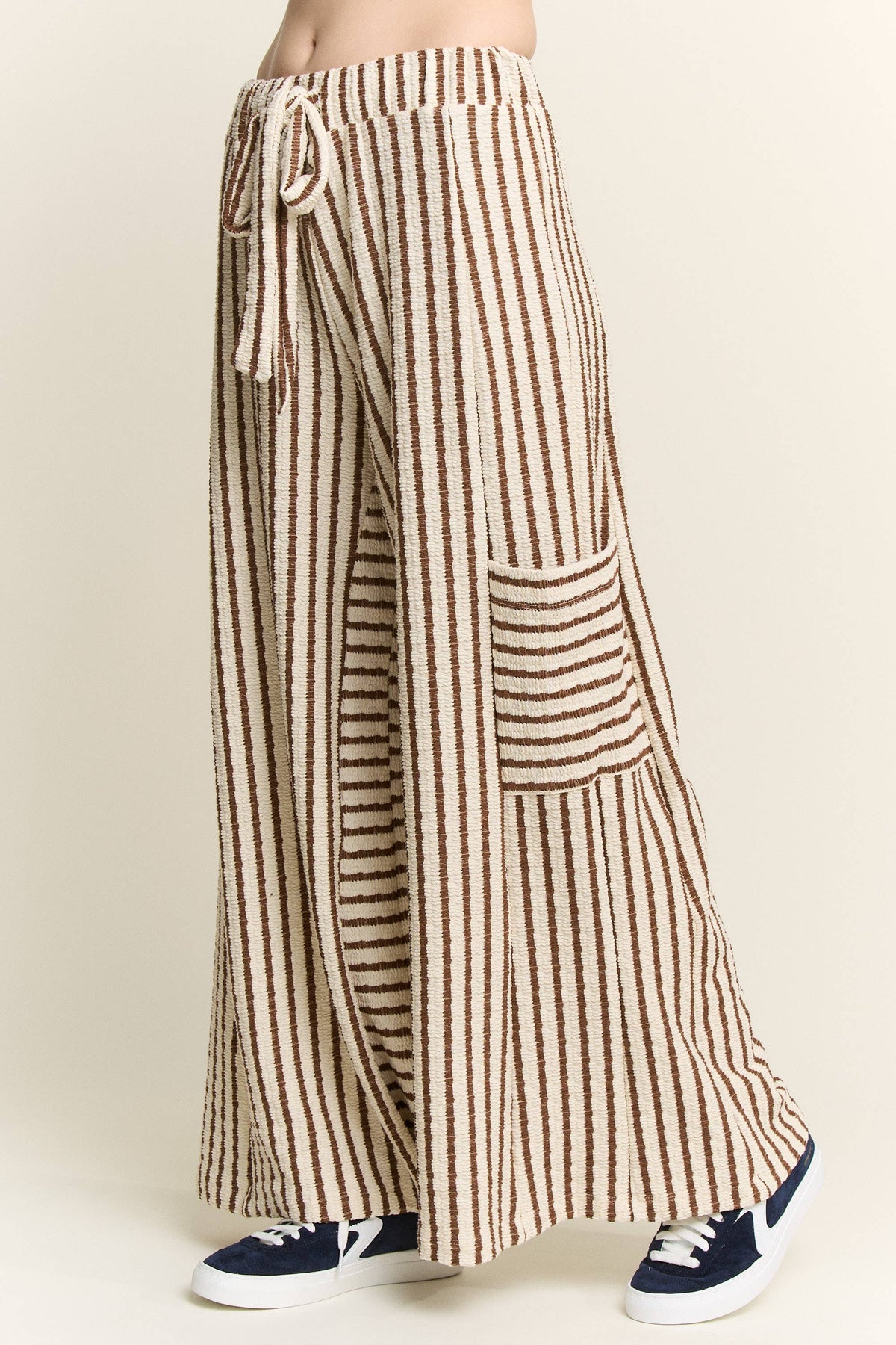 Brown and cream striped wide-leg pants featuring a drawstring waist, relaxed fit, and oversized front patch pockets.